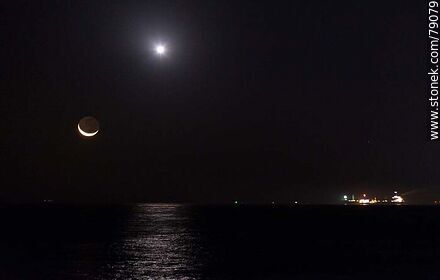 La luna nueva próxima a ocultarse en el mar frente al puerto de Montevideo. La luz de un avión que se dirige al aeropuerto y un barco de carga - Departamento de Montevideo - URUGUAY. Foto No. 79079