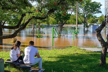 Pareja sentada frente a la Plaza de los Recuerdos inundada - Departamento de Salto - URUGUAY. Foto No. 86063